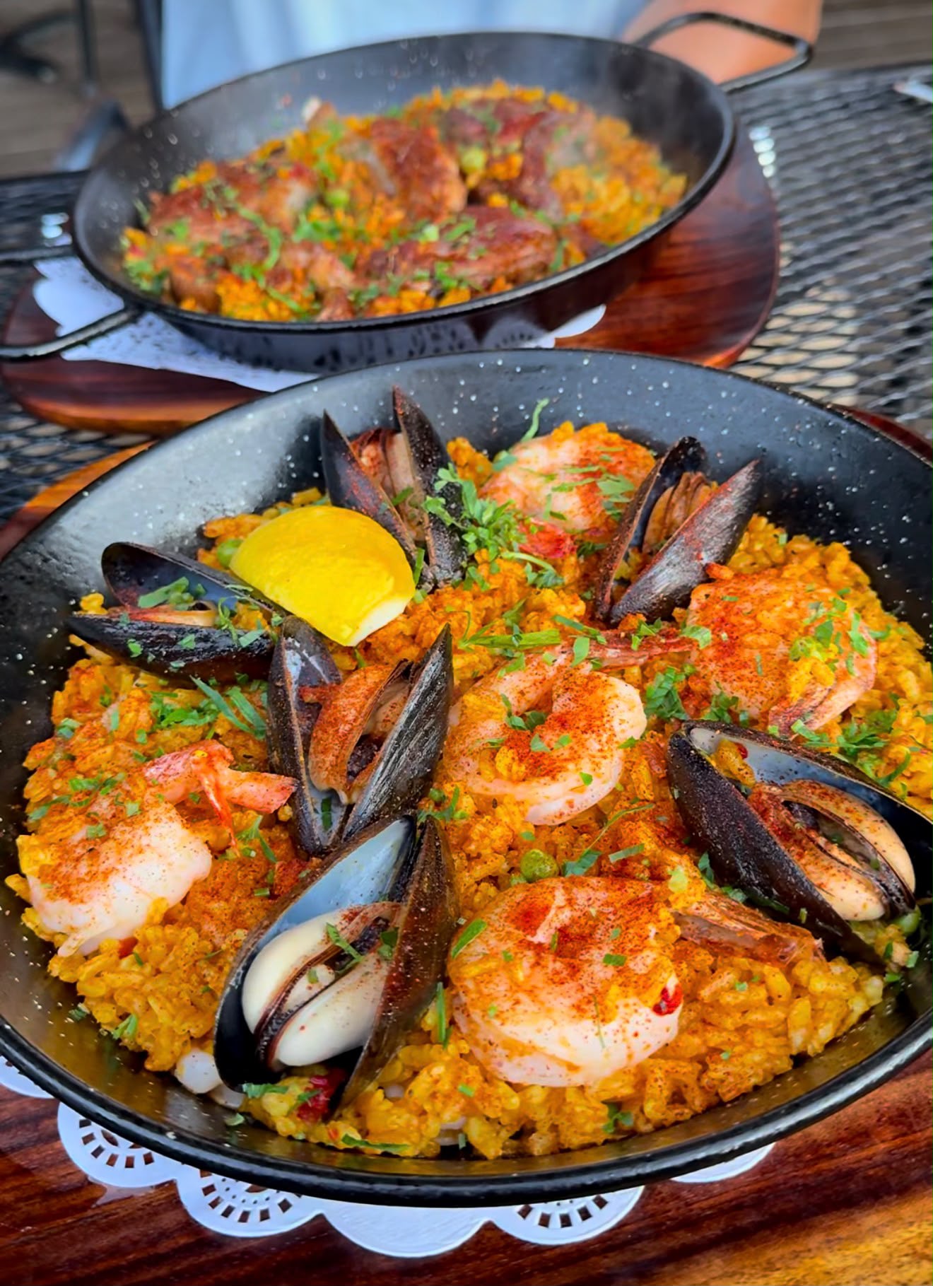 Two pans on the table — seafood in front