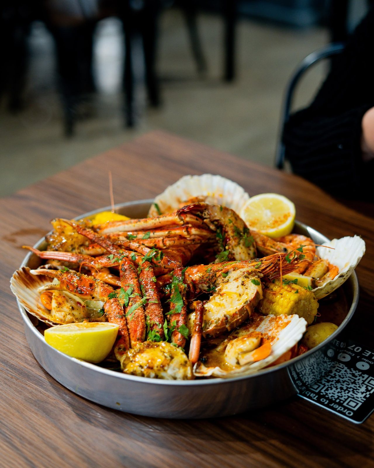 Rock & Scallop seafood boil in a steel tray with lobster tail, crab, king prawns, half-shell scallops, corn and lemon