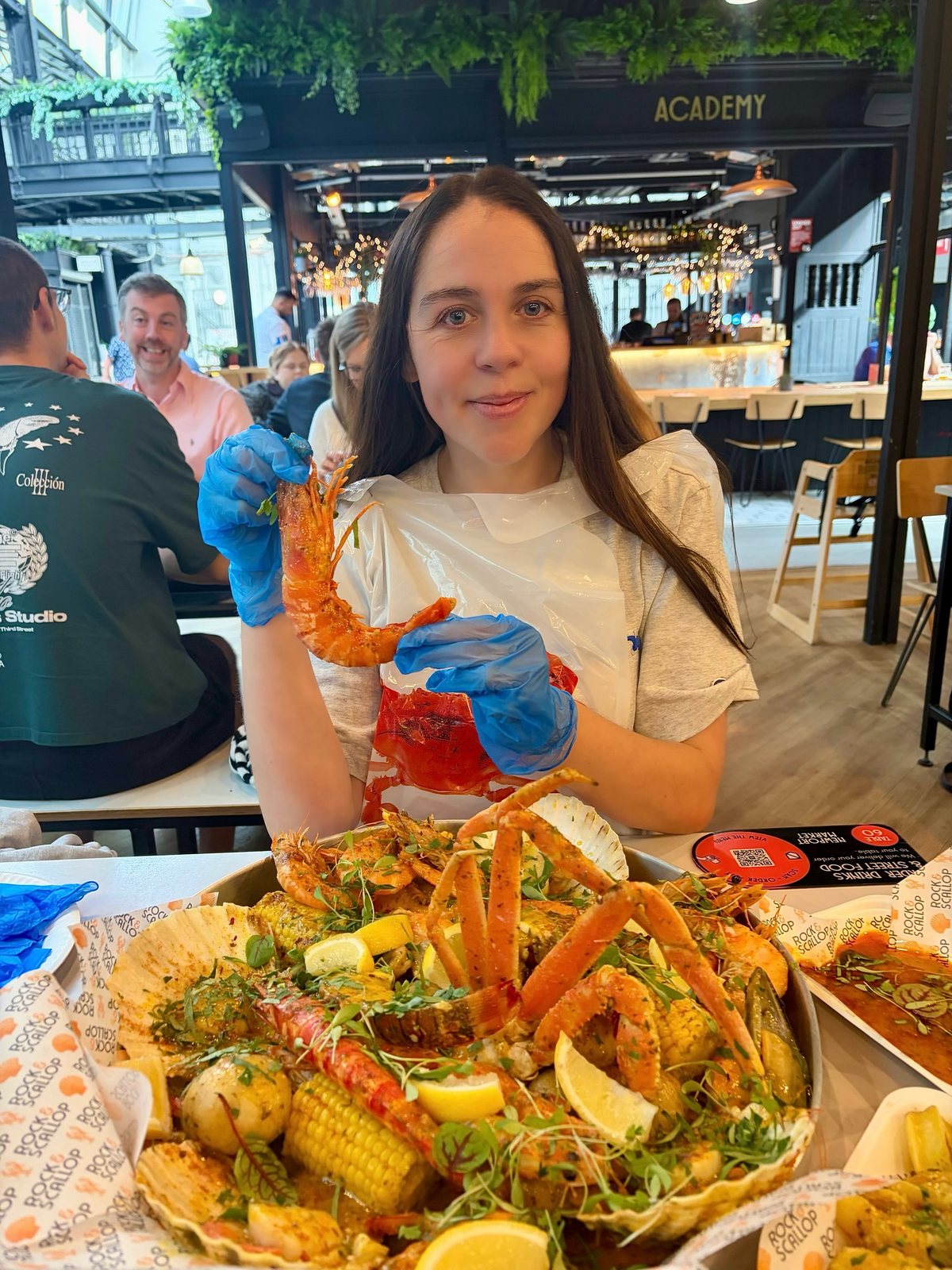 Diner in bib/gloves with seafood boil platter, market hall