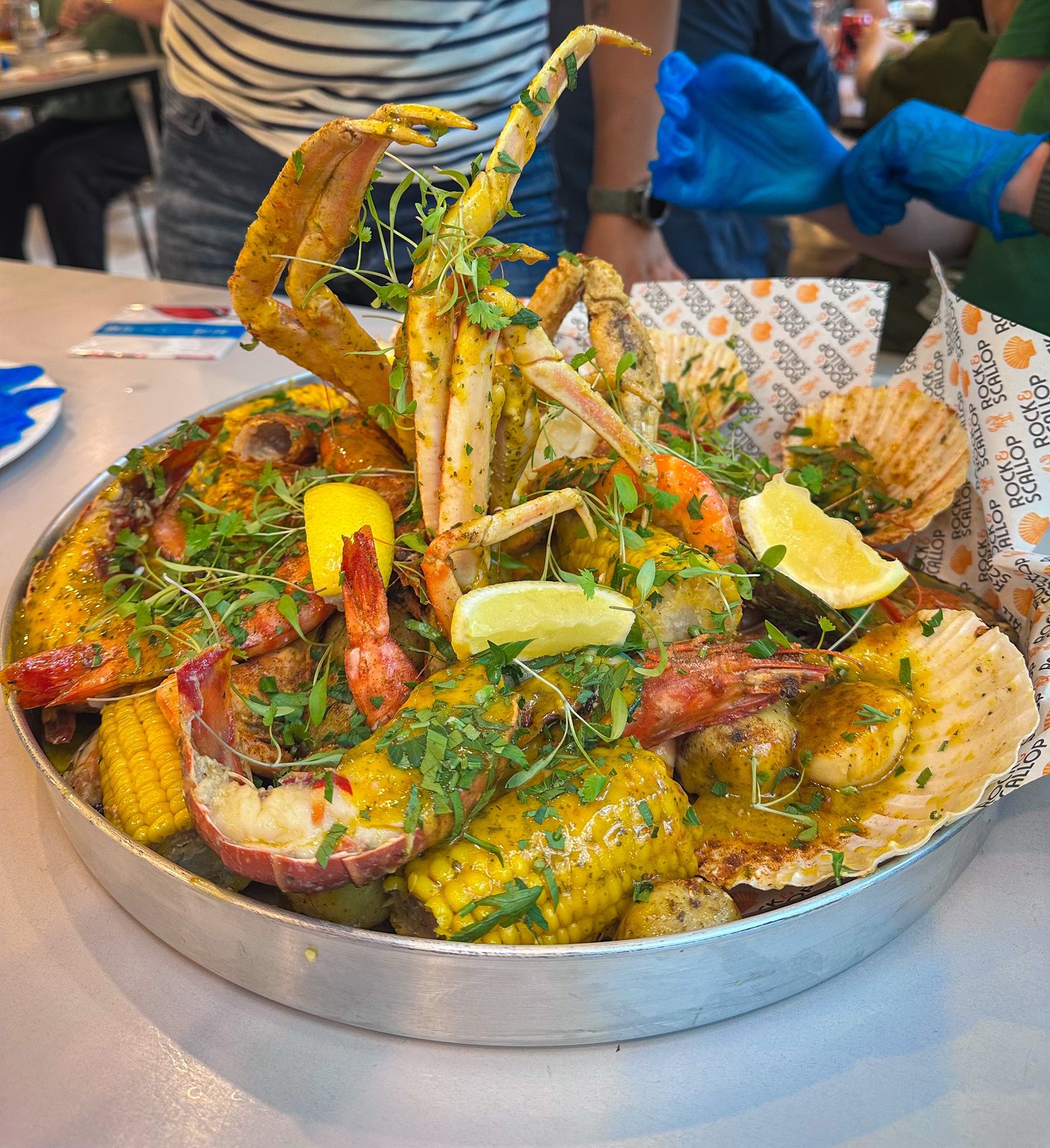 Close-up Deluxe Seafood Boil: lobster, snow crab, prawns, corn, potatoes, lemon, herbs