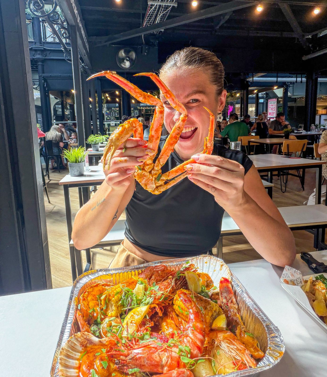 Diner holding crab leg over seafood boil tray