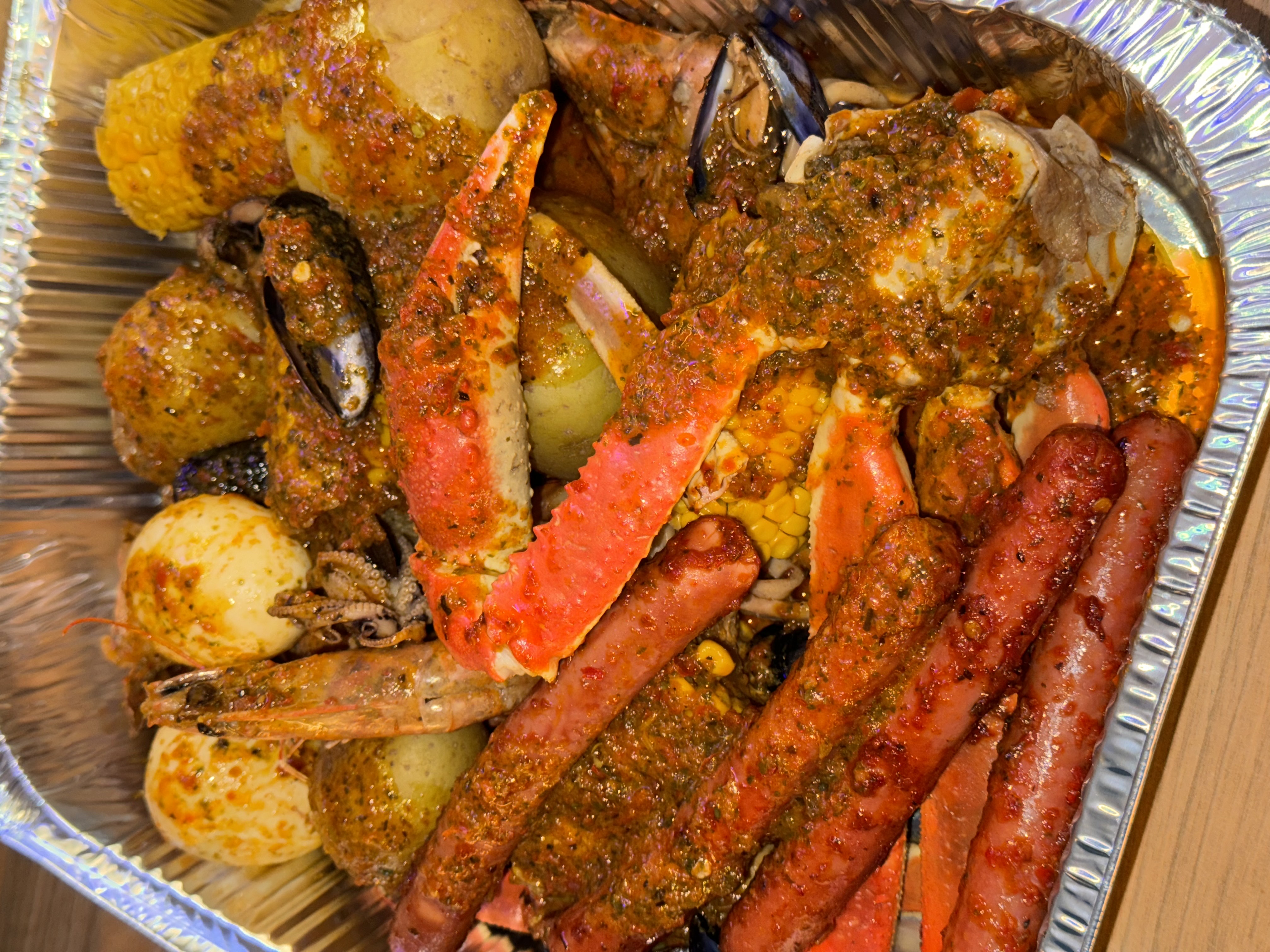 Seafood boil spread — crab, prawns, corn and potatoes (Coastal Delight menu)